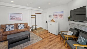A living room with a sofa, coffee table, TV, fireplace, and artwork on the walls. - Ski, Bike & Hike | Ultimate On-Mountain Location! (Mt Crested Butte)