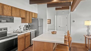 A modern kitchen with wooden cabinets, stainless steel appliances, and a central island with seating. - Vista Rubino. Bright Timberline condo with lift access, views, trails, and shuttle. (Mt Crested Butte)