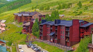 A hillside hotel with multiple buildings, a parking area, and a scenic view of the surrounding hills. - Vista Rubino. Bright Timberline condo with lift access, views, trails, and shuttle. (Mt Crested Butte)