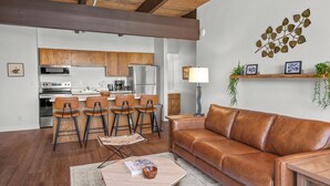 A modern kitchen with wooden cabinets, a stainless steel refrigerator, and a bar area with stools. - Vista Rubino. Bright Timberline condo with lift access, views, trails, and shuttle. (Mt Crested Butte)