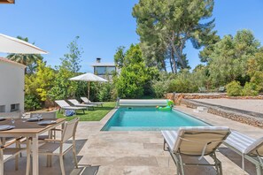 A pool area with lounge chairs, a dining table, and a view of trees and a building. - Villa Rosa Lia, swimming pool, pétanque, near the sea (Carqueiranne)