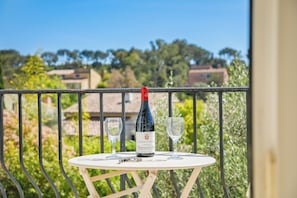Un balcon avec une table, une bouteille de vin et deux verres.