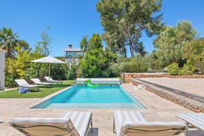 A swimming pool with lounge chairs, a sun umbrella, and a stone wall. - Villa Rosa Lia, swimming pool, pétanque, near the sea (Carqueiranne)