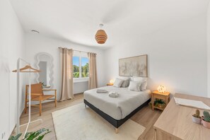 A modern bedroom with a bed, bedside table, lamp, and a view of greenery outside. - Villa Rosa Lia, swimming pool, pétanque, near the sea (Carqueiranne)