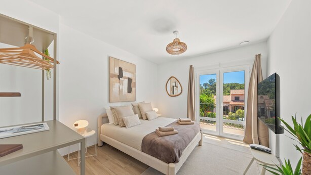 A modern bedroom with a bed, a TV, a desk, and a window with a view of greenery. - Villa Rosa Lia, swimming pool, pétanque, near the sea (Carqueiranne)