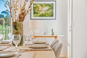 Une table à manger dressée avec des assiettes, des verres et un vase contenant des branches.