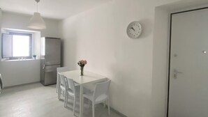 Eine moderne Küche mit weißen Schränken, einem Kühlschrank und einem Essbereich mit weißem Tisch und Stühlen.