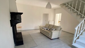 Ein geräumiger Wohnbereich mit einer Couch, einer Treppe und einem Kamin.
