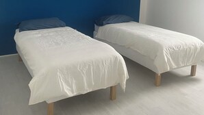 Ein Schlafzimmer mit zwei Betten, einer blauen Akzentwand und einer weißen Deckenleuchte.