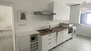 Eine moderne Küche mit weißen Schränken, einem Gasherd, einem Backofen und einer Waschmaschine.