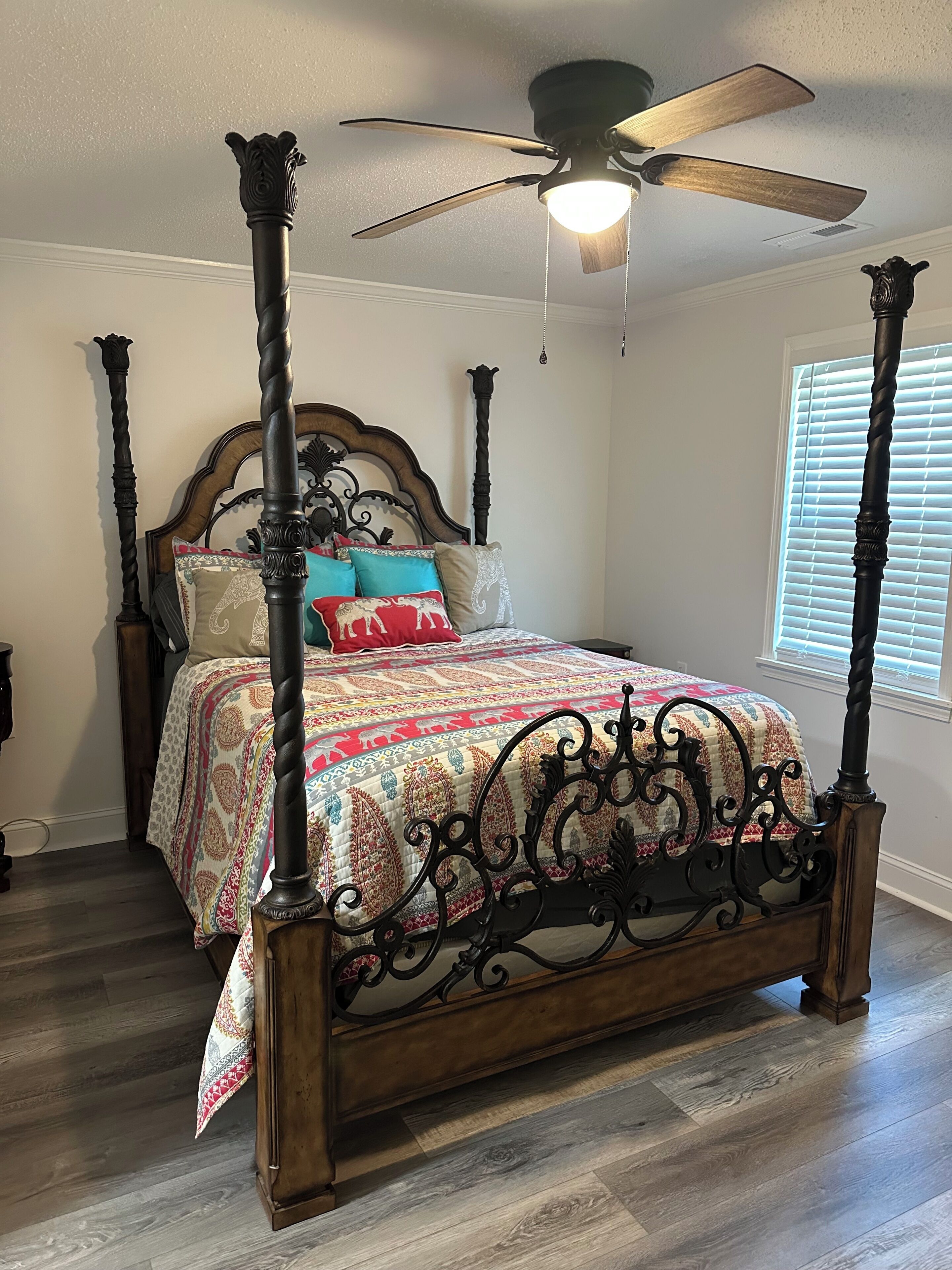 A four-poster bed with a wooden frame and a ceiling fan above.