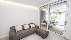 Una sala de estar moderna con un sofá modular, un ventanal de vidrio que da a un patio exterior y vistas al exterior.