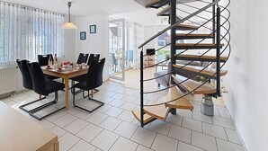 Ein modernes Interieur mit Essbereich, Wendeltreppe und Blick durch eine Glastür.
