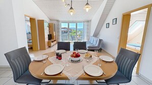 En matplats med ett bord för fyra personer, stolar, en tv och utsikt över omgivningen.