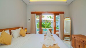 Une chambre d’hôtel avec un lit, une tête de lit en bois, un miroir et une vue sur l’espace extérieur abritant une piscine.