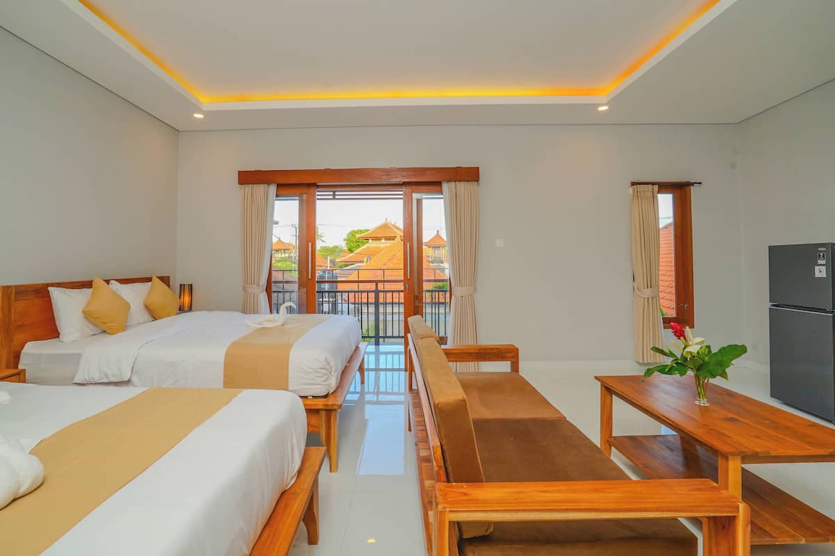 A hotel room with two beds, a wooden bench, a table, and a view of a residential area.