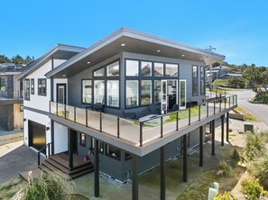 Une maison moderne à deux étages, dotée de grandes fenêtres, d’un balcon et d’un garage.