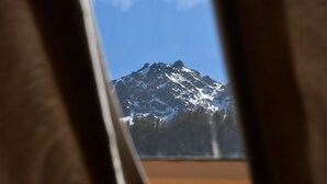 Une montagne vue à travers une fenêtre, avec un ciel dégagé.