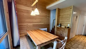 Un coin repas en bois avec une table et des chaises, un banc et des lampes suspendues.