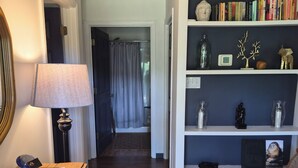 A hallway with wooden flooring, a lamp, a desk with papers, a bookshelf with books and decorative items, and a door leading to another room. - Enjoyable 2-bedroom cottage in Afton Virginia.
1.5 miles from the best winery! (Afton)