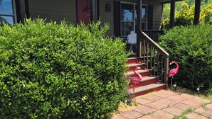 A house with a covered porch, a red door, and a staircase leading to the entrance. - Enjoyable 2-bedroom cottage in Afton Virginia.
1.5 miles from the best winery! (Afton)