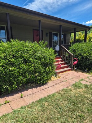 A house with a covered porch, a red door, and a staircase leading to the entrance. - Enjoyable 2-bedroom cottage in Afton Virginia.
1.5 miles from the best winery! (Afton)