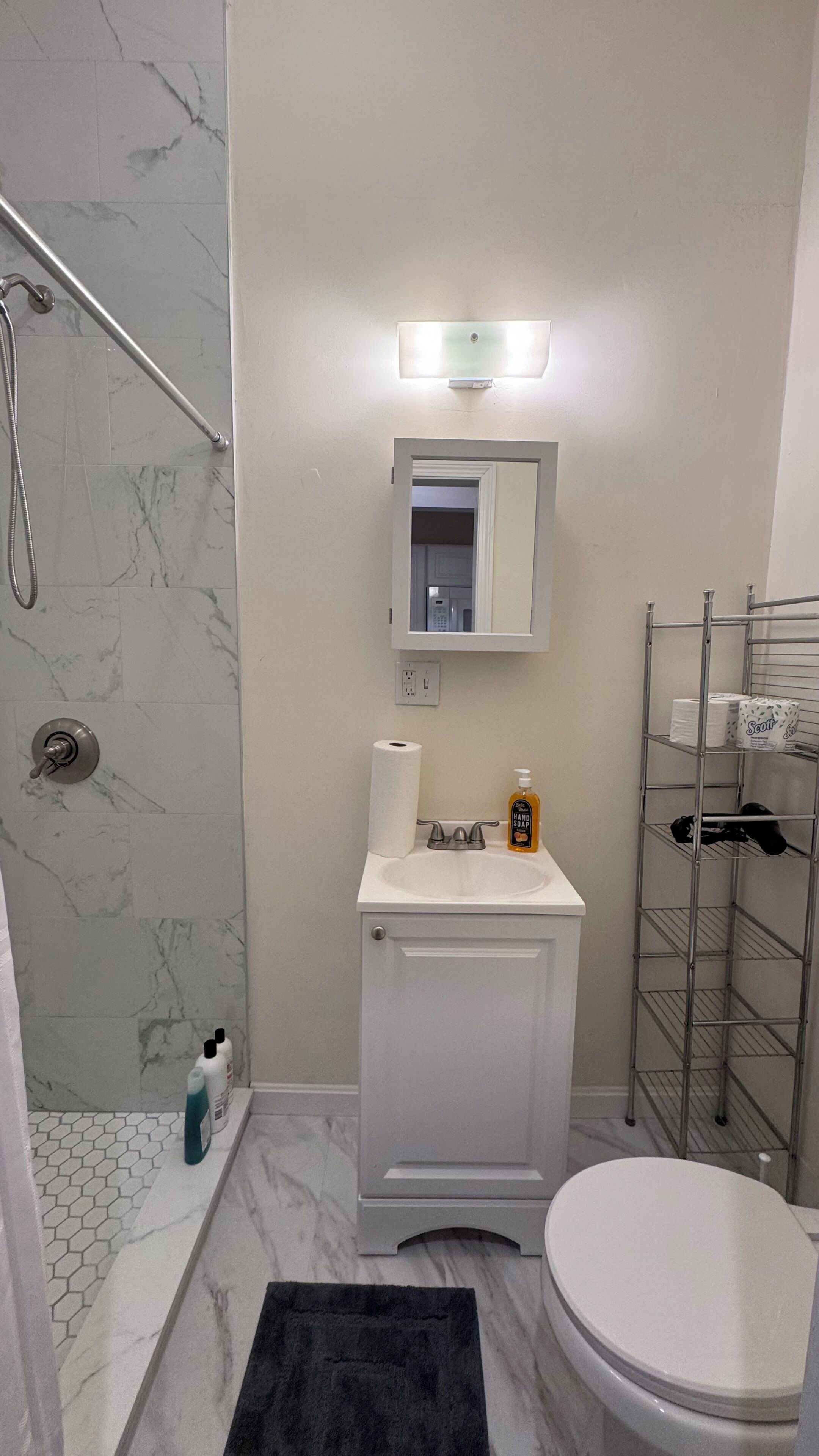 Un baño con ducha, inodoro, lavabo y un espejo sobre el lavabo.