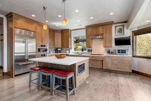 Una cocina moderna con armarios de madera, electrodomésticos de acero inoxidable y una isla grande con taburetes.