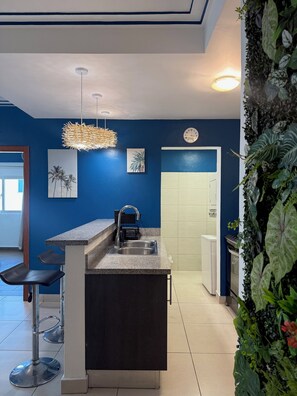 Een moderne keuken met een bar, een klok en een wandplant.
