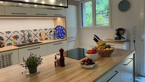 A modern kitchen with a wooden countertop, a sink, a window, and a clock on the wall. - Spacious Landes villa with swimming pool, in the heart of the pines (Soorts-Hossegor)