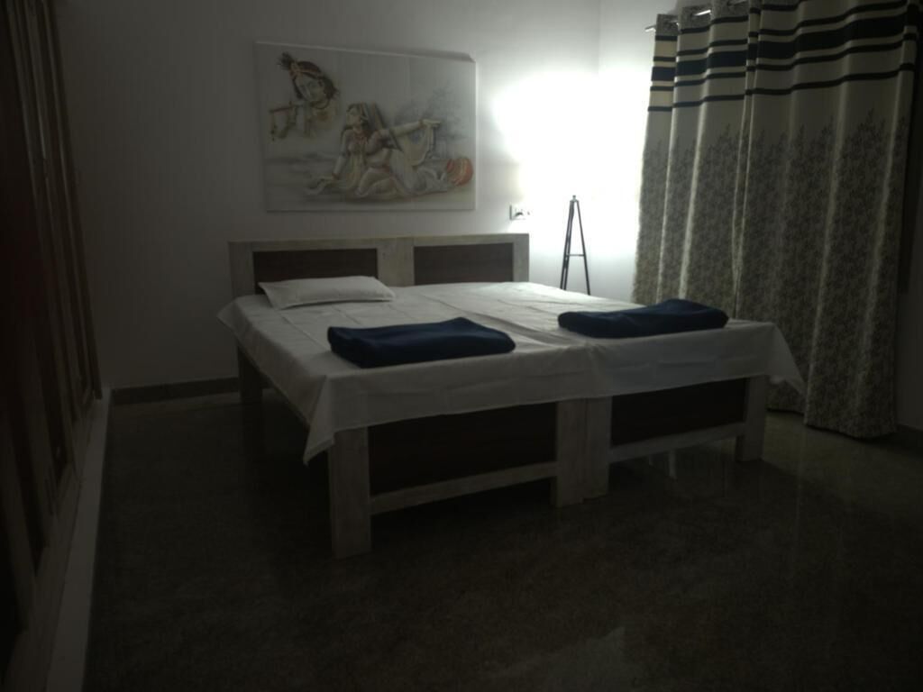 Un dormitorio con cama, un cuadro en la pared y una ventana con cortinas.