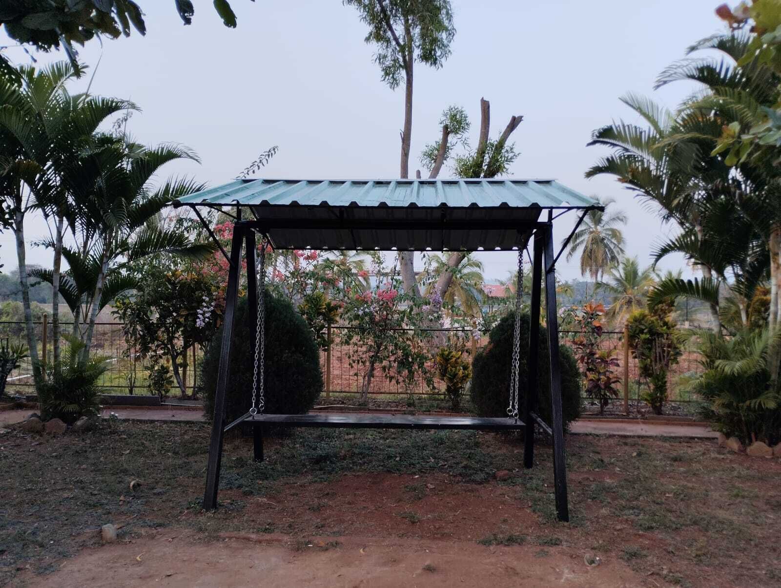 A garden with a swing set and a metal roof structure.