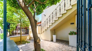Un patio con un árbol, una escalera y una jardinera blanca con flores.