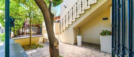 A courtyard with a tree, a staircase, and a white planter with flowers.