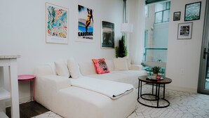 Ein Wohnzimmer mit einem weißen Sofa, einem kleinen runden Tisch und einem Blumentopf.