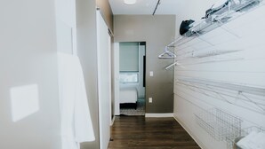 Ein Flur mit Holzboden, weißer Wand und einem Bett im Hintergrund.
