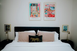 A neatly made bed with two pillows, a leopard print pillow, and two framed artworks above it. - Charming 2-bedroom apartment with Balcony/ Garage Parking in Cambridge (Cambridge)
