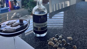Une bouteille de martini au café expresso ZARITA sur un comptoir de cuisine, avec un verre de la boisson, une assiette blanche et des coquillages.
