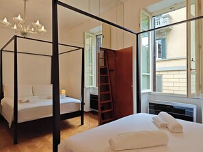 A four-poster bed, a wooden ladder, a window with shutters, and a radiator. - Casa Albania Rome (Roma)