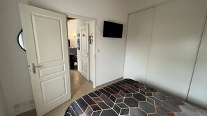 Ein Schlafzimmer mit einem Bett, einem an der Wand montierten Fernseher und einer Tür zu einem Badezimmer.