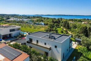Un edificio moderno con tetto piatto, pannelli solari e vista su un lago.