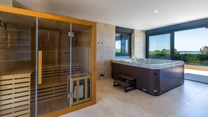 Een moderne spa-ruimte met een sauna, een whirlpool en een groot raam met uitzicht.