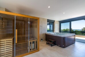 A modern spa room with a sauna, a hot tub, and a large window offering a view. - Villa Jura – Modern Villa with Pool, Wellness and Sea View (Peroj)