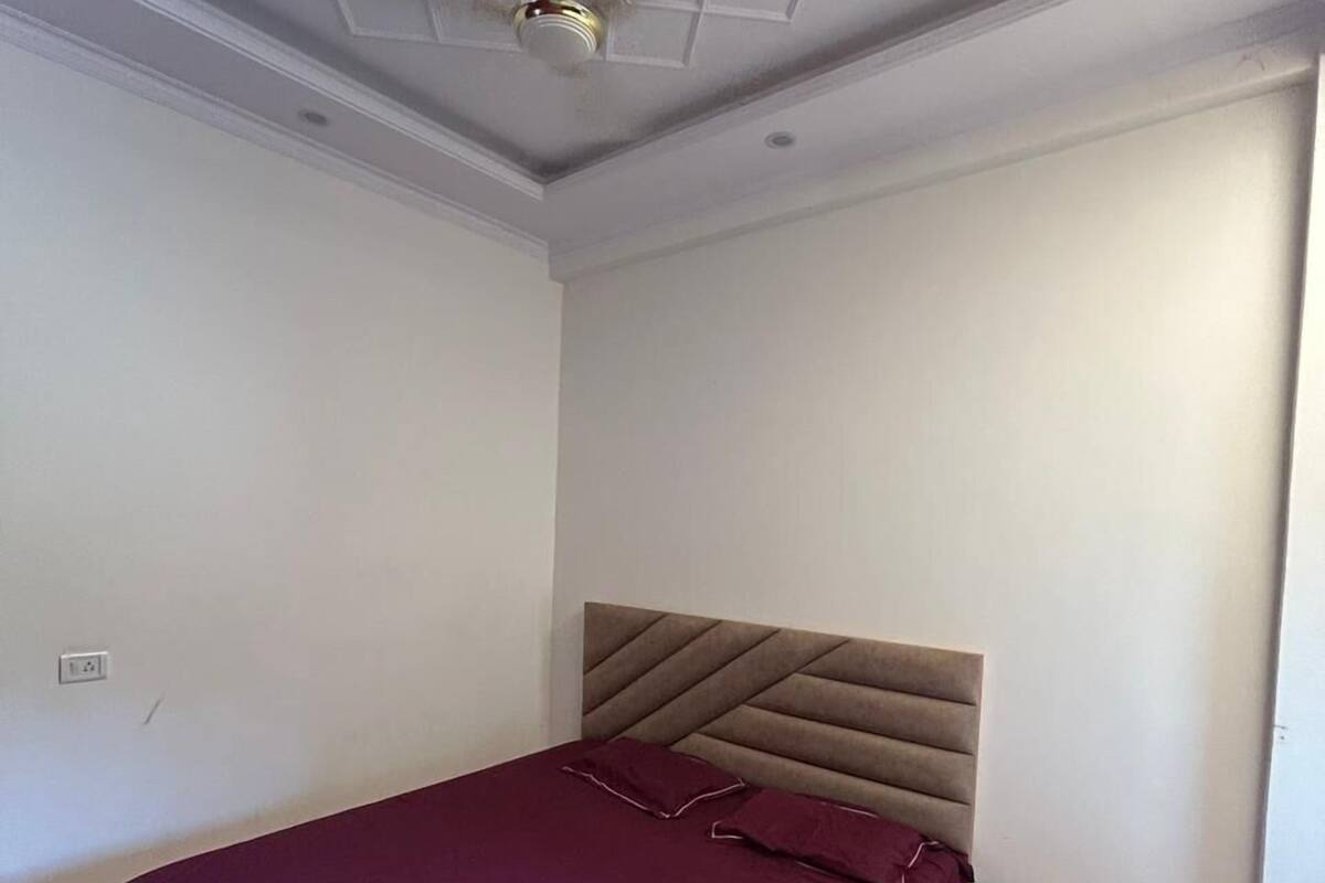 A bedroom with a bed, a ceiling fan, a nightstand, and a small dresser.