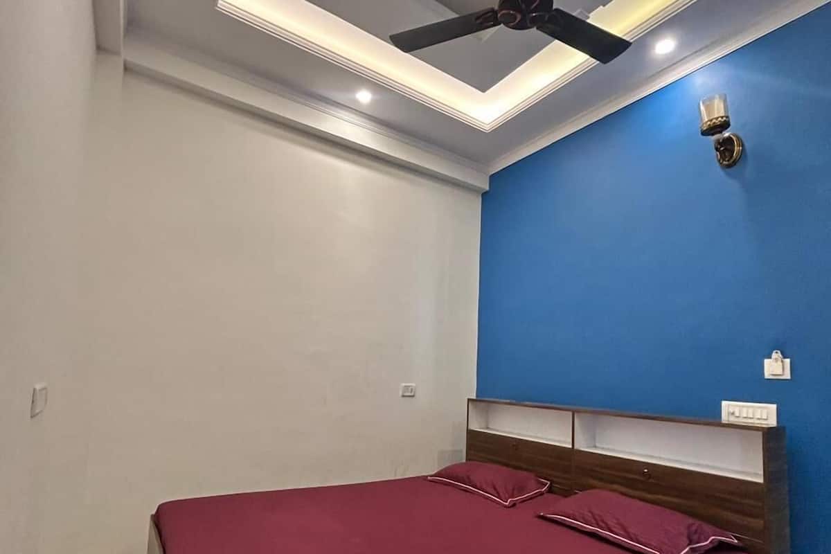 Ein Schlafzimmer mit einem Bett, einem Deckenventilator, eingelassener Beleuchtung, einer blauen Akzentwand und einem Holz-Kopfstück.