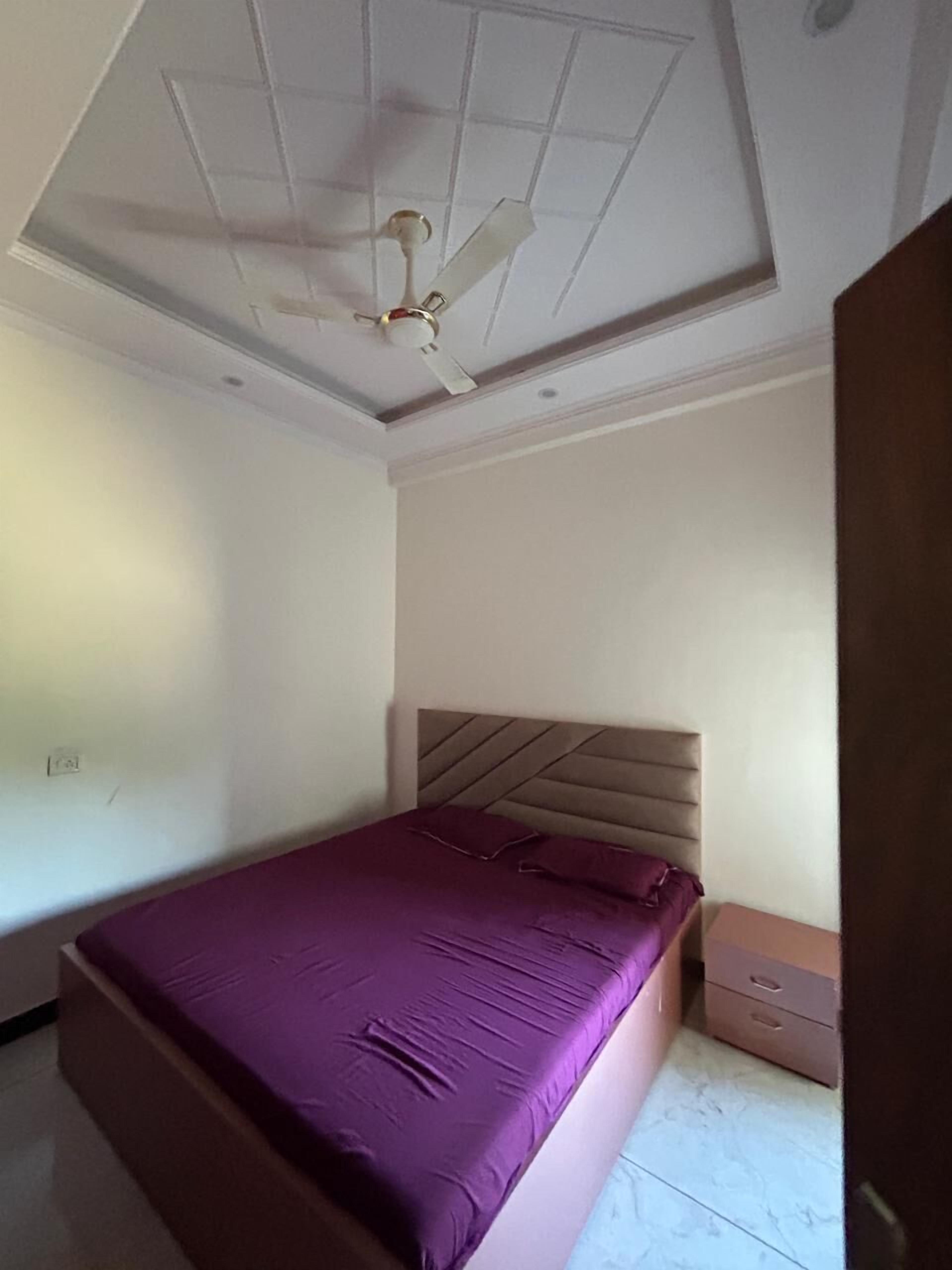 A bedroom with a bed, a ceiling fan, a nightstand, and a dresser.