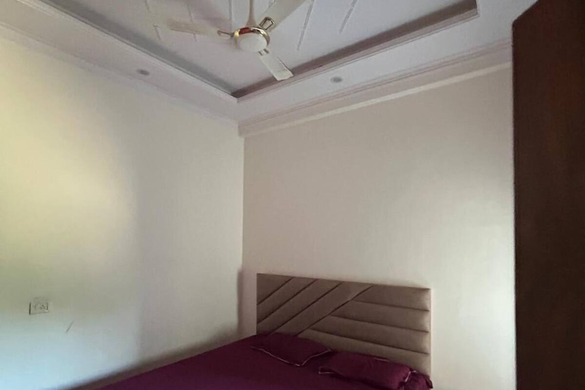 A bedroom with a bed, a ceiling fan, a nightstand, and a dresser.