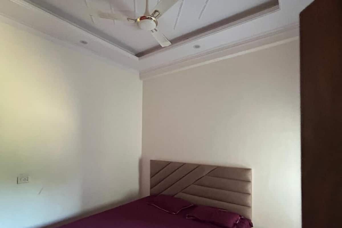 Ein Schlafzimmer mit Bett, Deckenventilator, Nachttisch und Kommode.