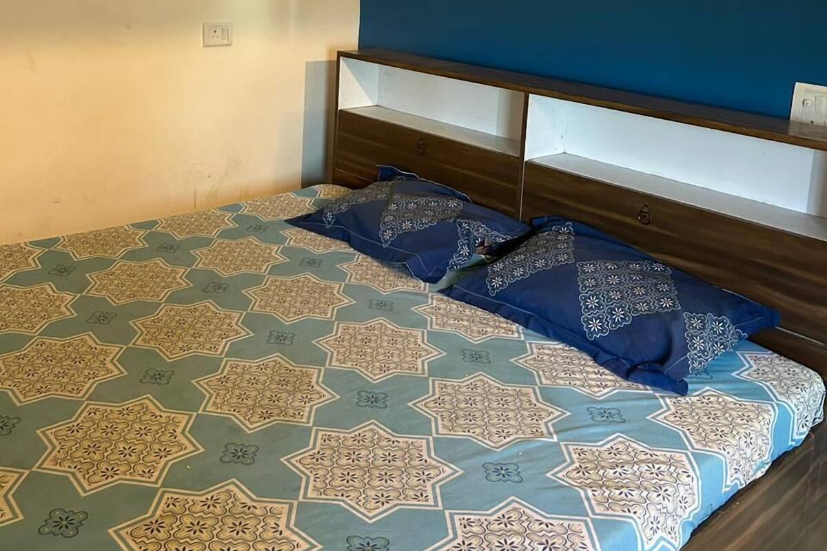 A bedroom with a bed, a nightstand, and a wall socket.