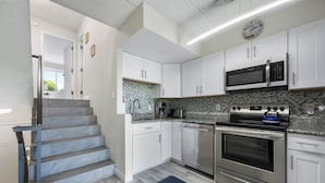 A modern kitchen with white cabinets, stainless steel appliances, and a tiled backsplash. - ADORABLE AND SPACIOUS 2 BR, 2 BA CONDO ... ON REHOBOTH AVE - 18 THE ARK (Rehoboth Beach)